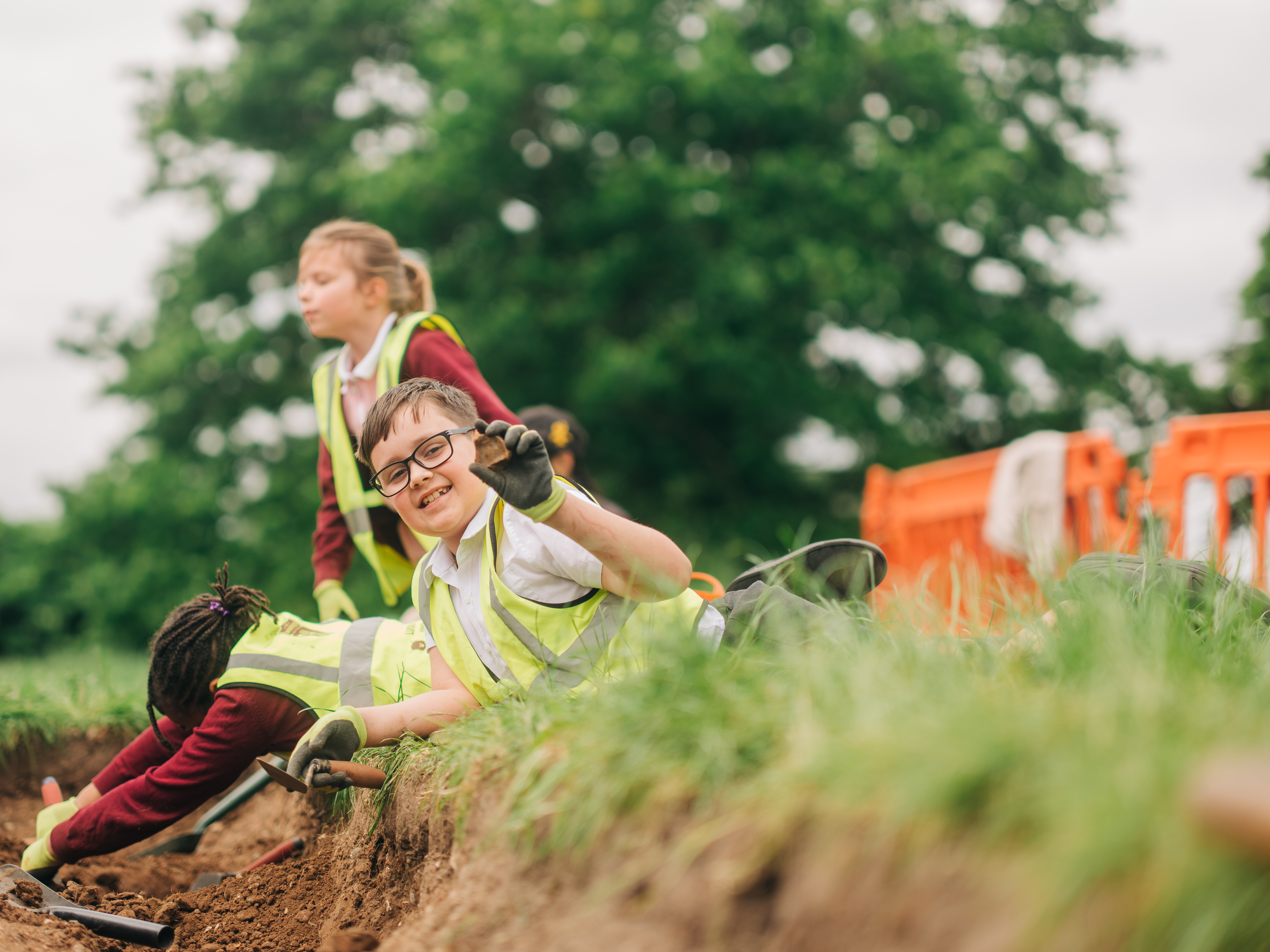 A child holds up something they have found during the dig