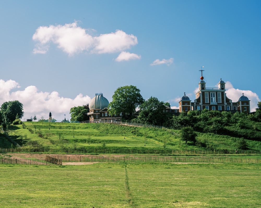 A view of the grand ascent in Greenwich Park on a sunny day with the Royal Observatory in the background. 