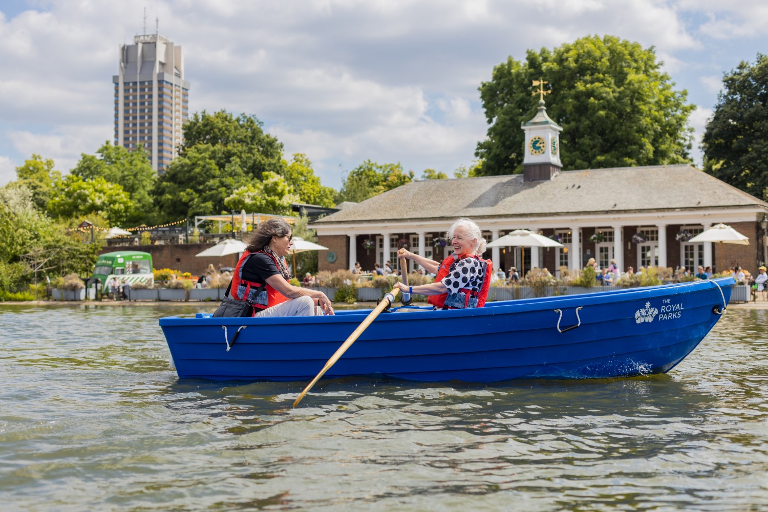 Park visitors in a rowing boat, with the Lido Café in the background