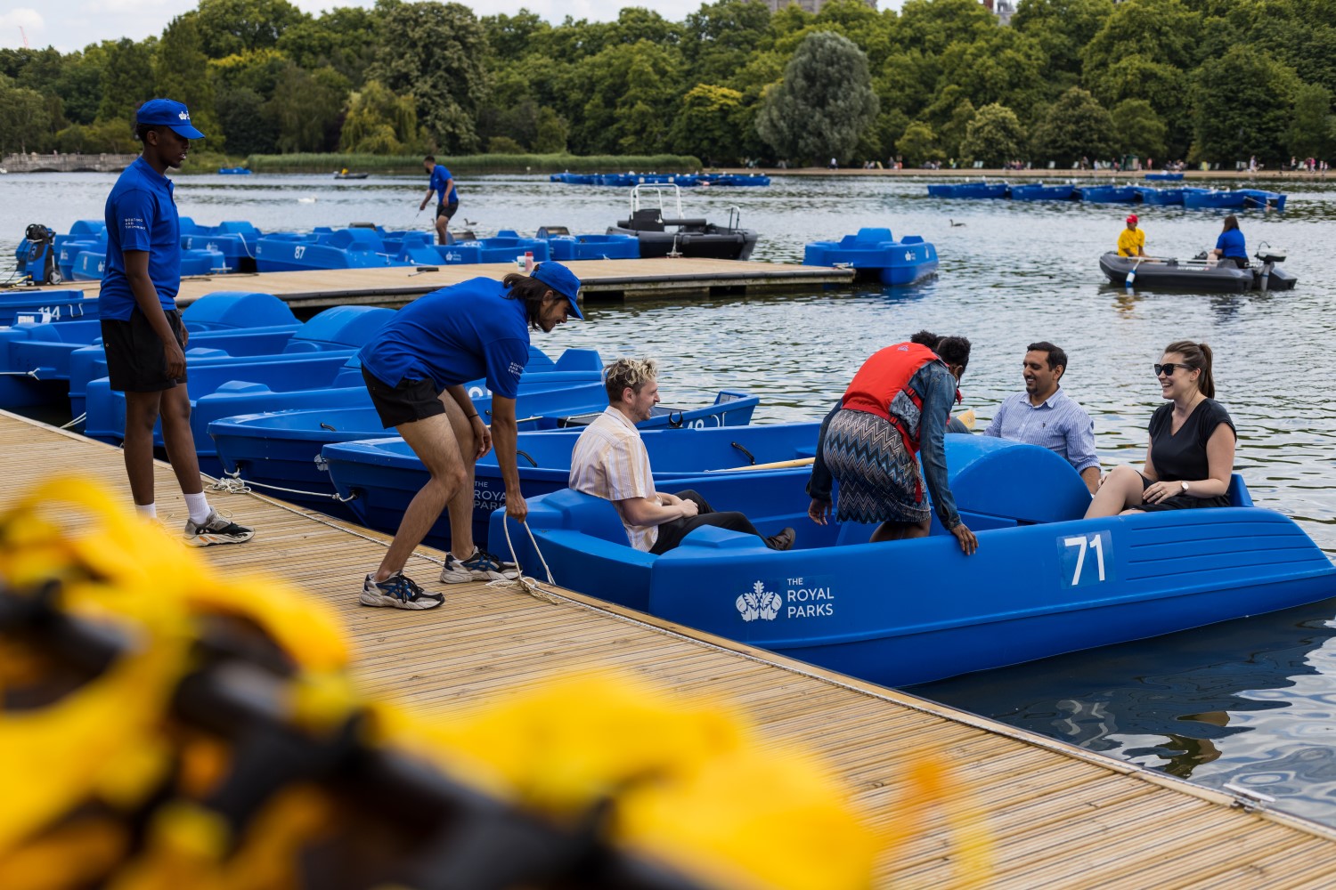 Staff launch a visitor's boat from the pontoon in The Serpentine