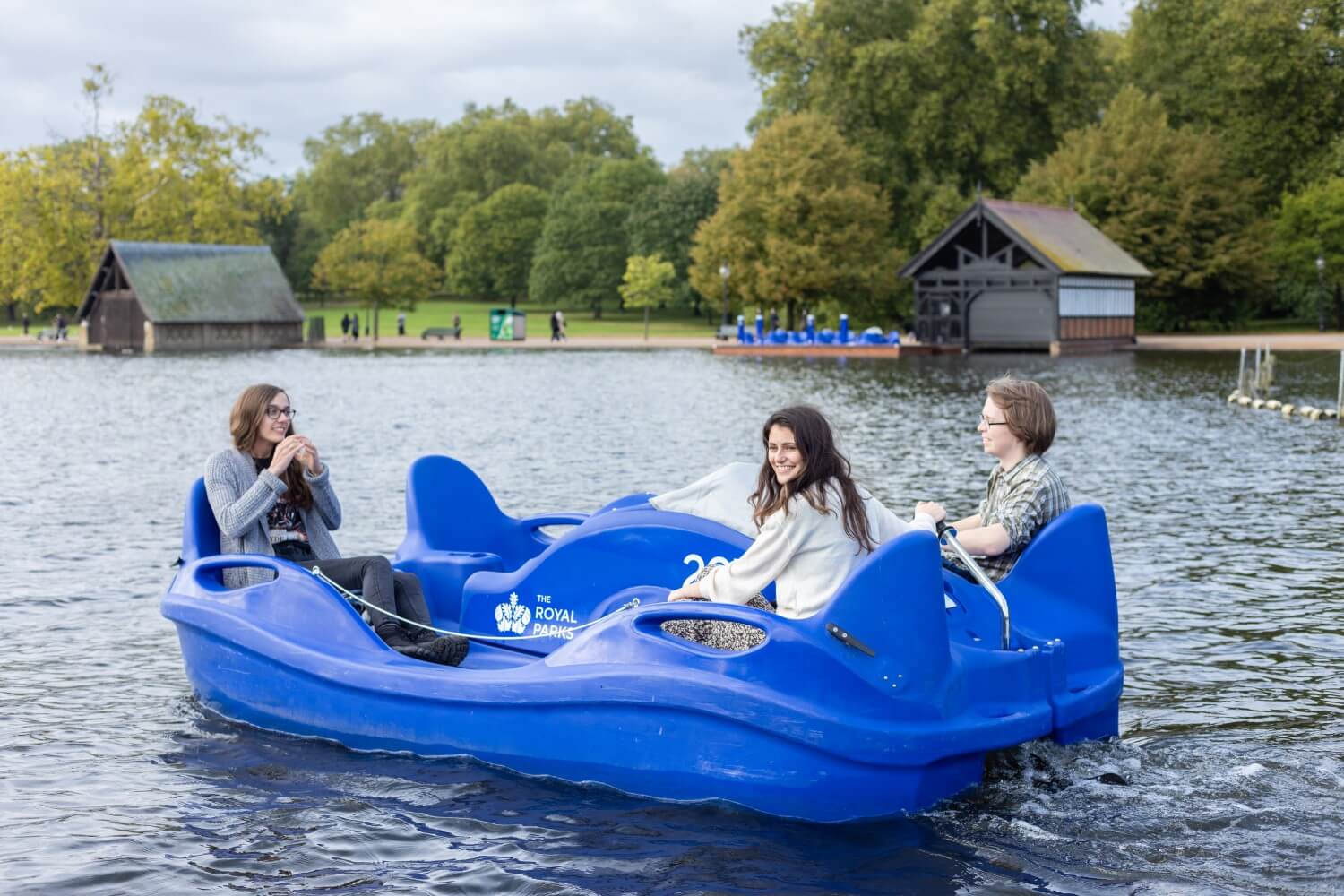 Three people ride an electric pedalo on the Serpentine in Hyde Park