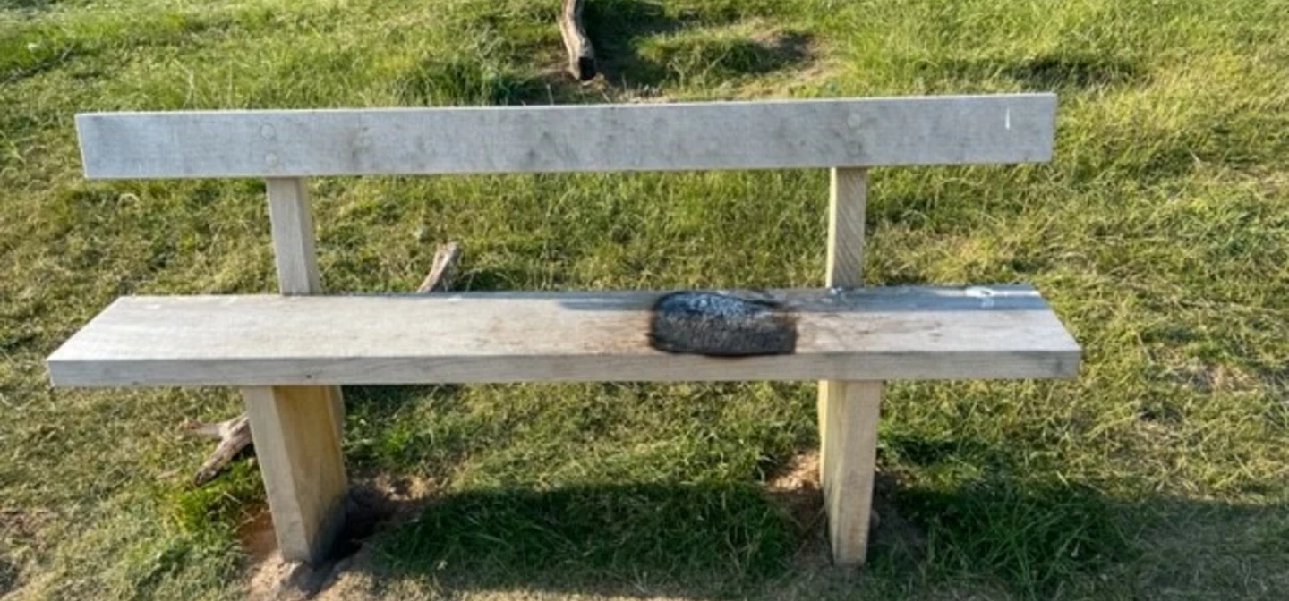 Park bench burnt by a portable barbecue