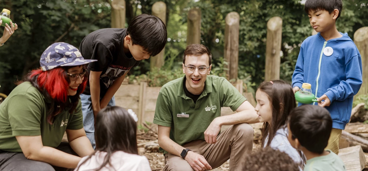 Image a guide in an outdoor setting, talking to a circle of children.