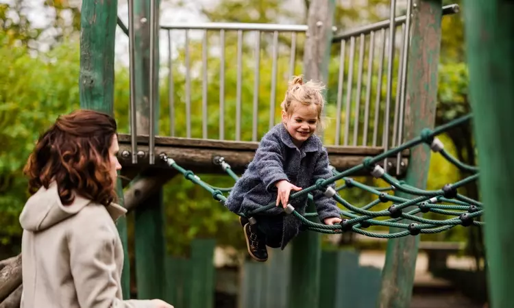 Young girl on a playground rope bridge