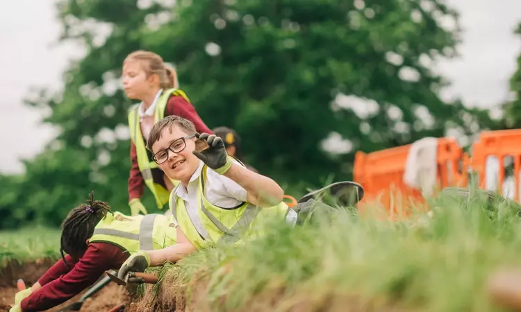 A child holds up something they have found during the dig