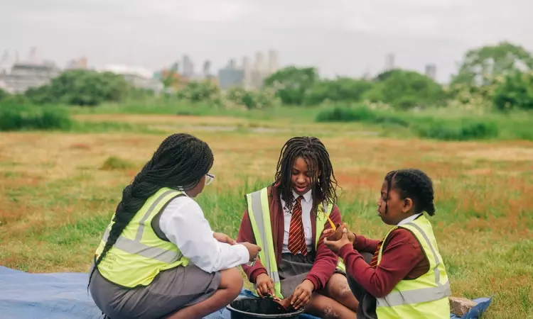 Three girls look over their finds with the view over London in the background