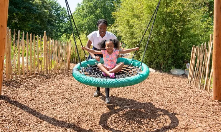 Parent and child on the big swing in Greenwich Playground in summer