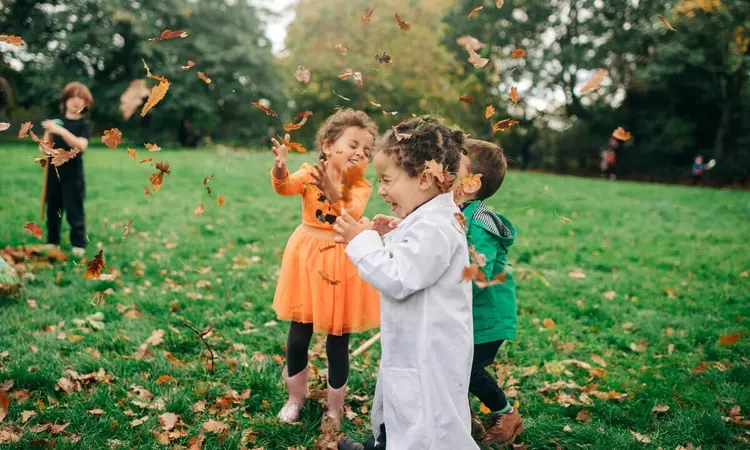 Children playing with leaves at Halloween