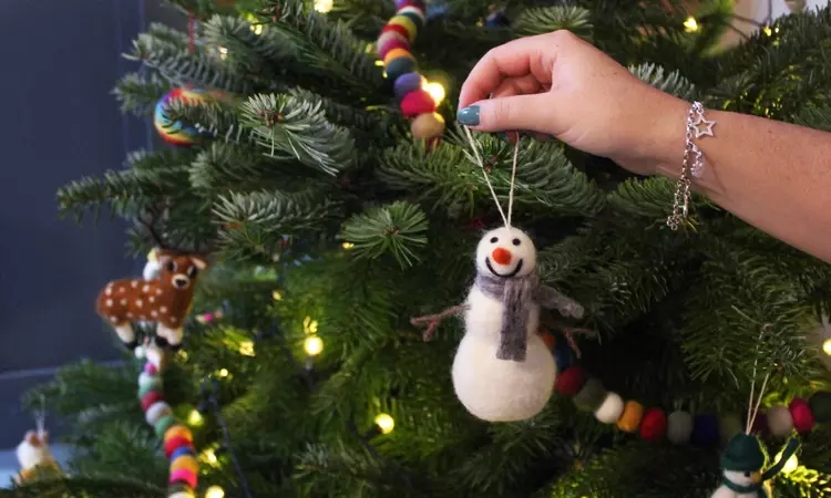 Felt snowman being hung on a Christmas tree