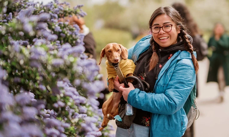 A young woman holding a small dog