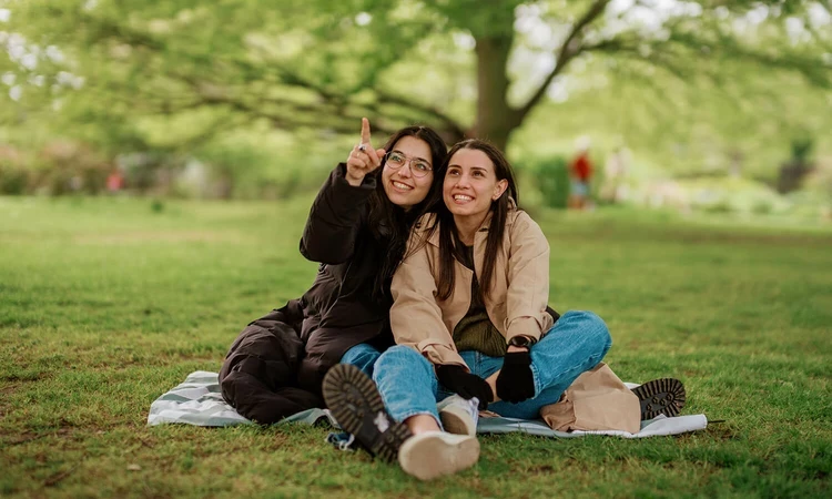 Two women sitting under the trees, looking up