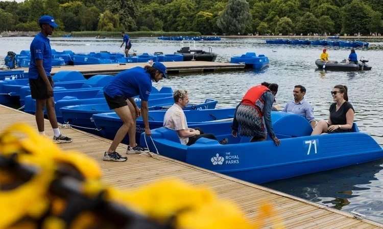 Staff launch a visitor's boat from the pontoon in The Serpentine
