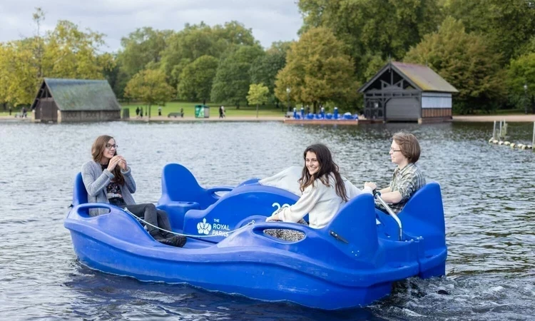 Three people ride an electric pedalo on the Serpentine in Hyde Park