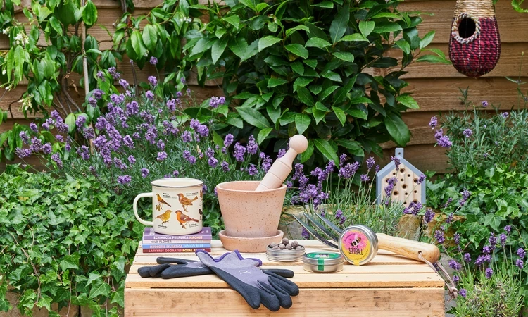 Gardening items available from the online shop including gloves, seeds and pots set against a garden backdrop