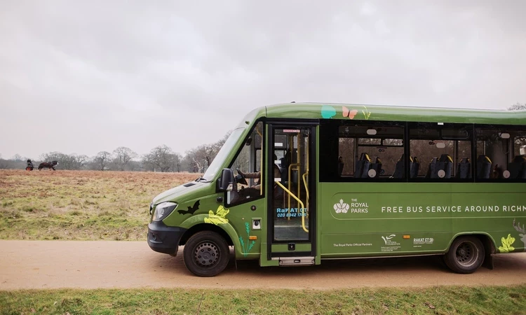 A side view of a green minibus going through Richmond Park