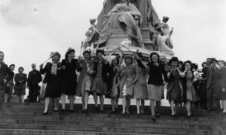 Women celebrate VE Day on the steps of the Queen Victoria Memorial outside Buckingham Palace