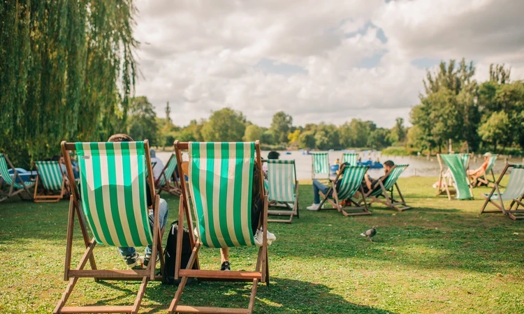 Green and white striped deck chairs in an outdoor, park setting.