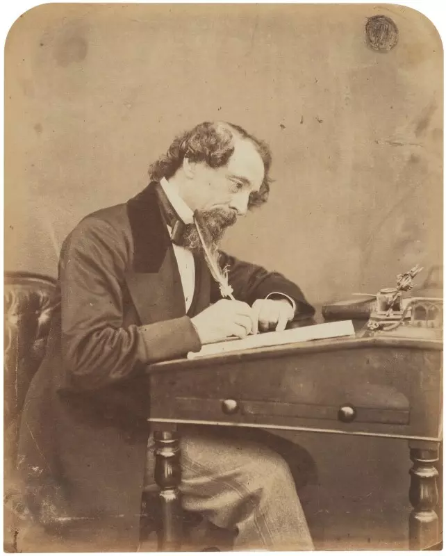 Photograph of Charles Dickens writing at his desk, 1858