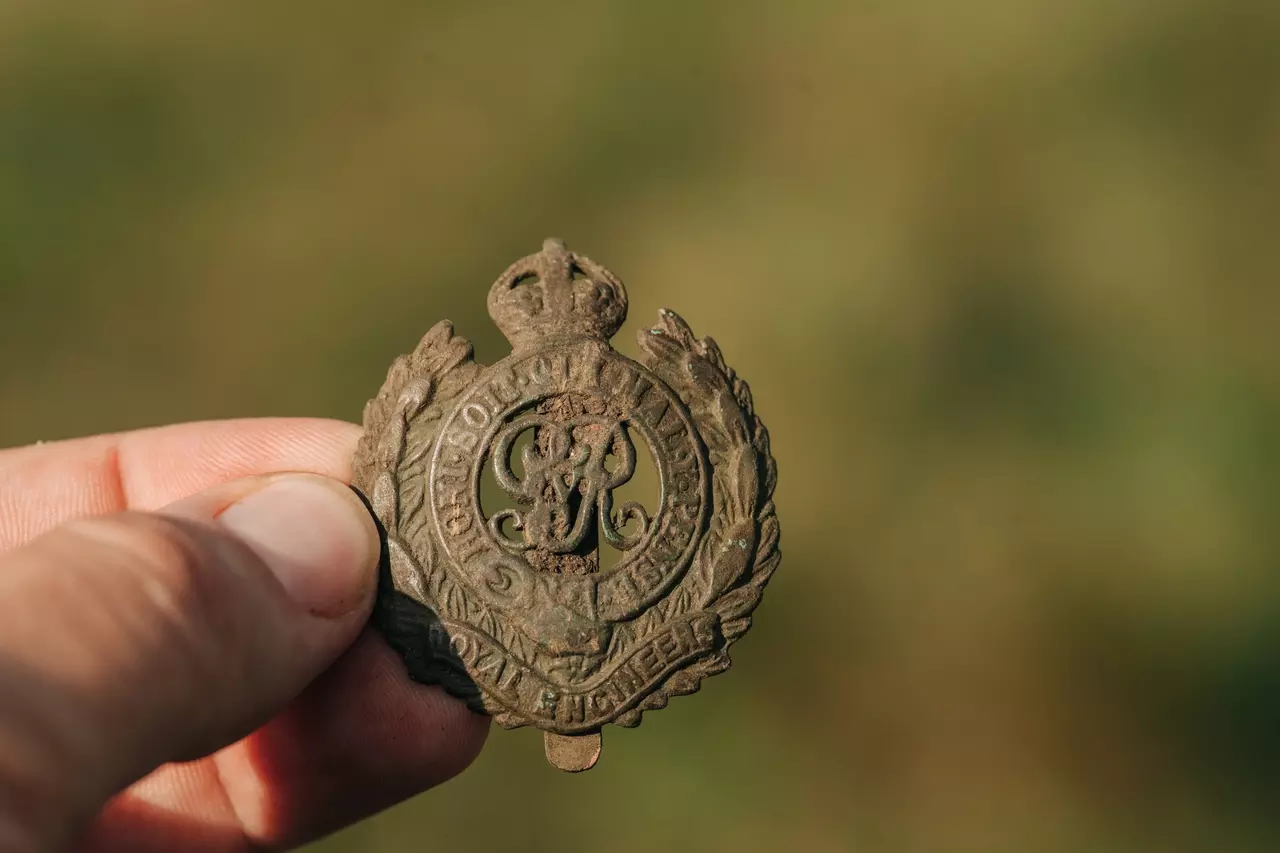 A image of someone holding a small Royal Engineers pin found in the trench