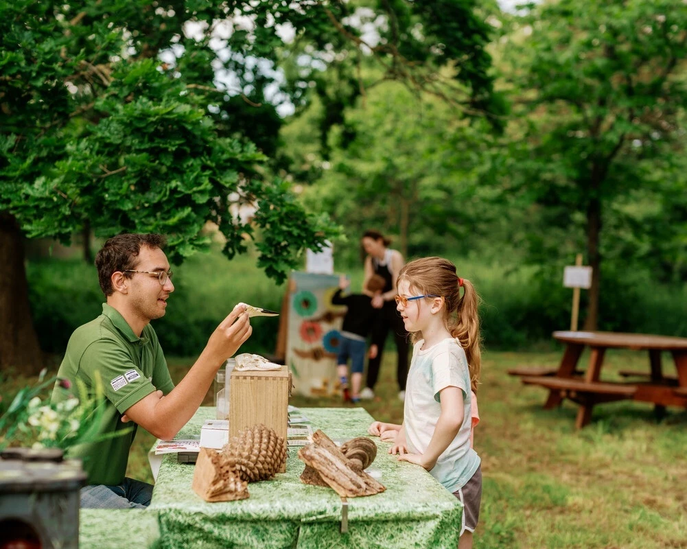 Little girl talking to staff from the Help Nature Thrive team who is showing her something