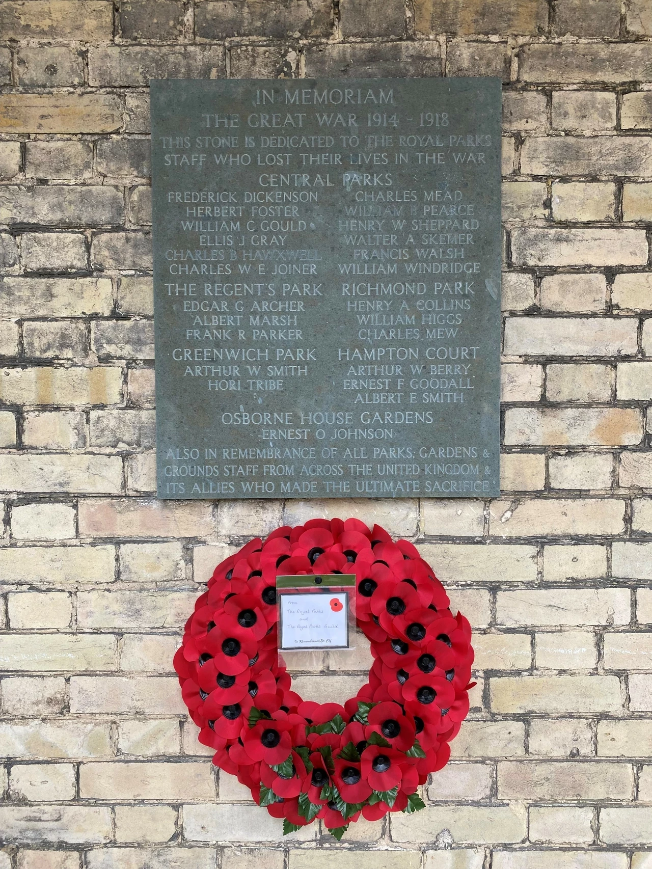 A plaque commemorating the Royal Parks employees who died during the First World War - a wreath of poppies hangs beneath it