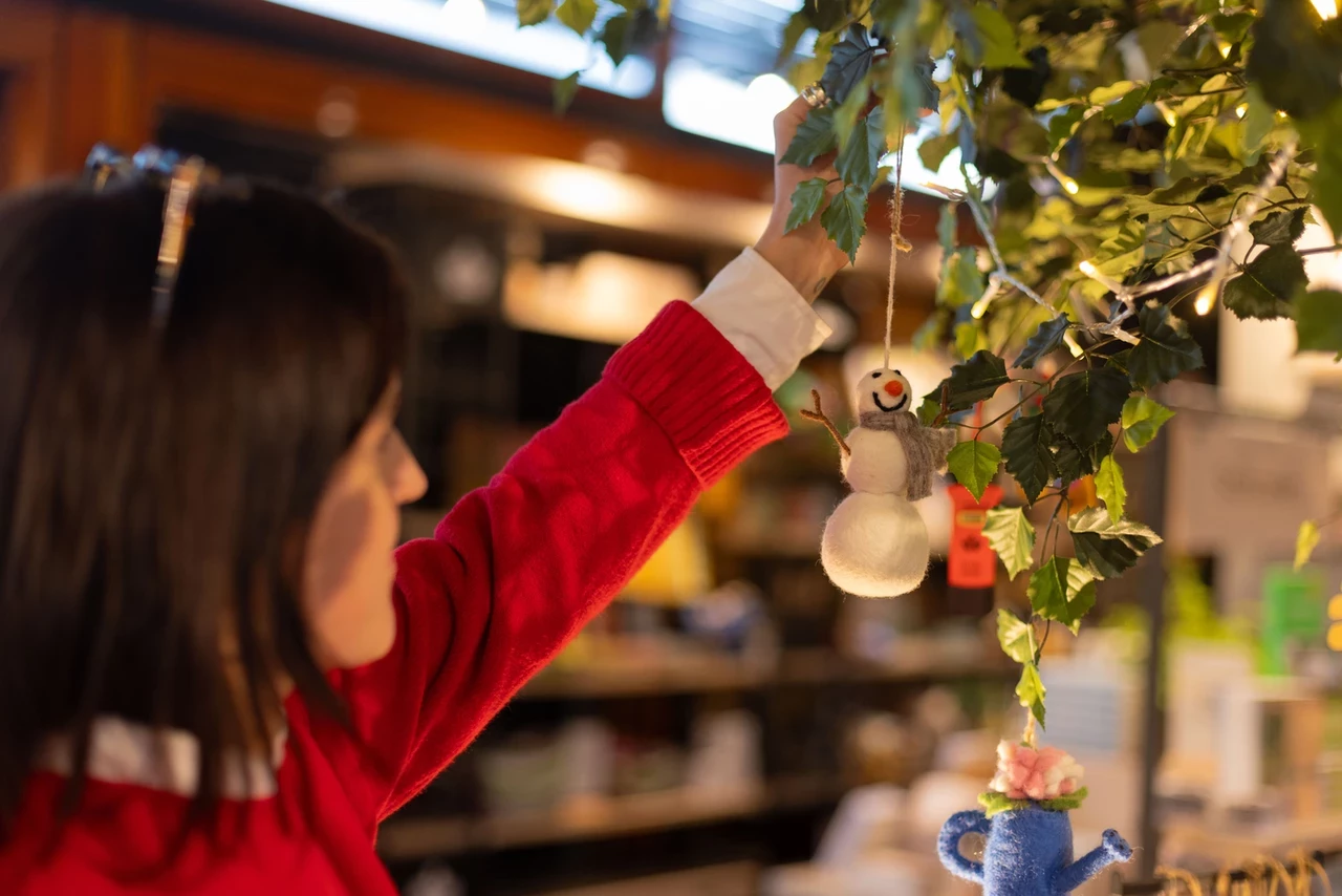 Woman hanging Christmas ornament on tree