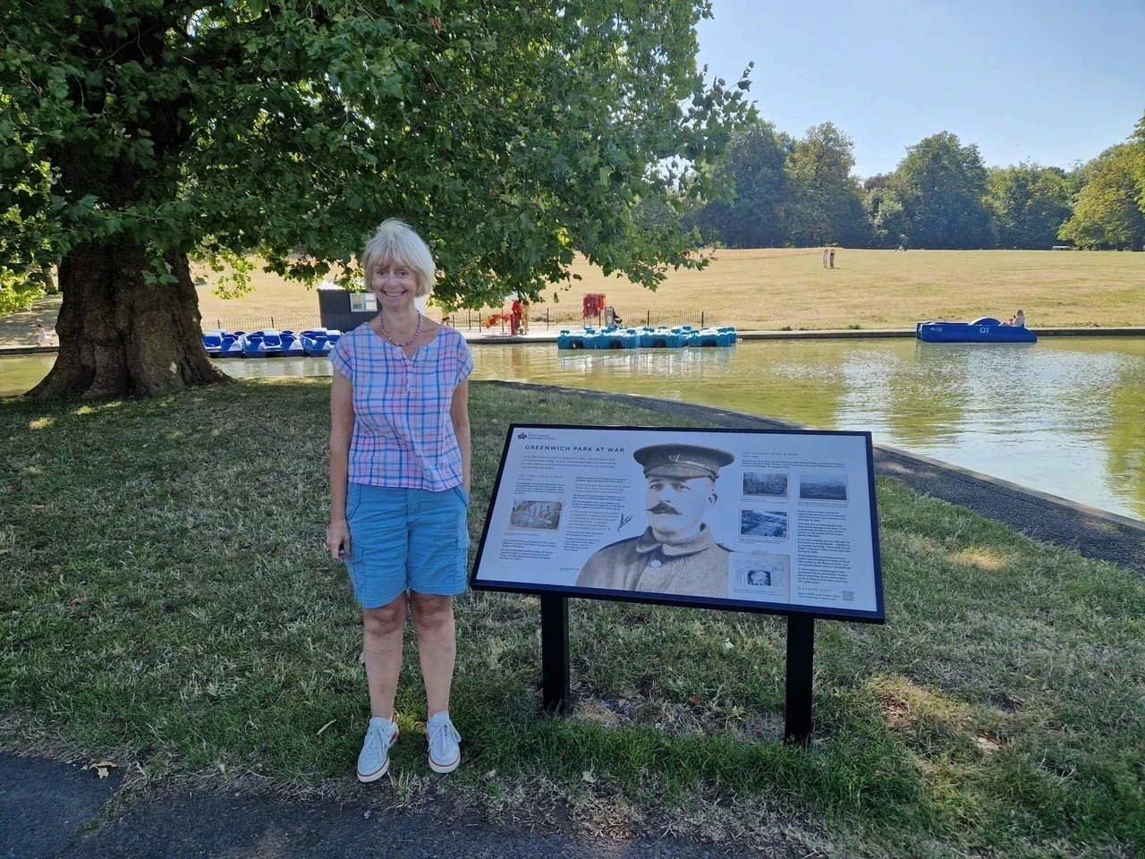 Sarah Gooch stands next to the new information board celebrating Hori Tribe's story at Greenwich Park